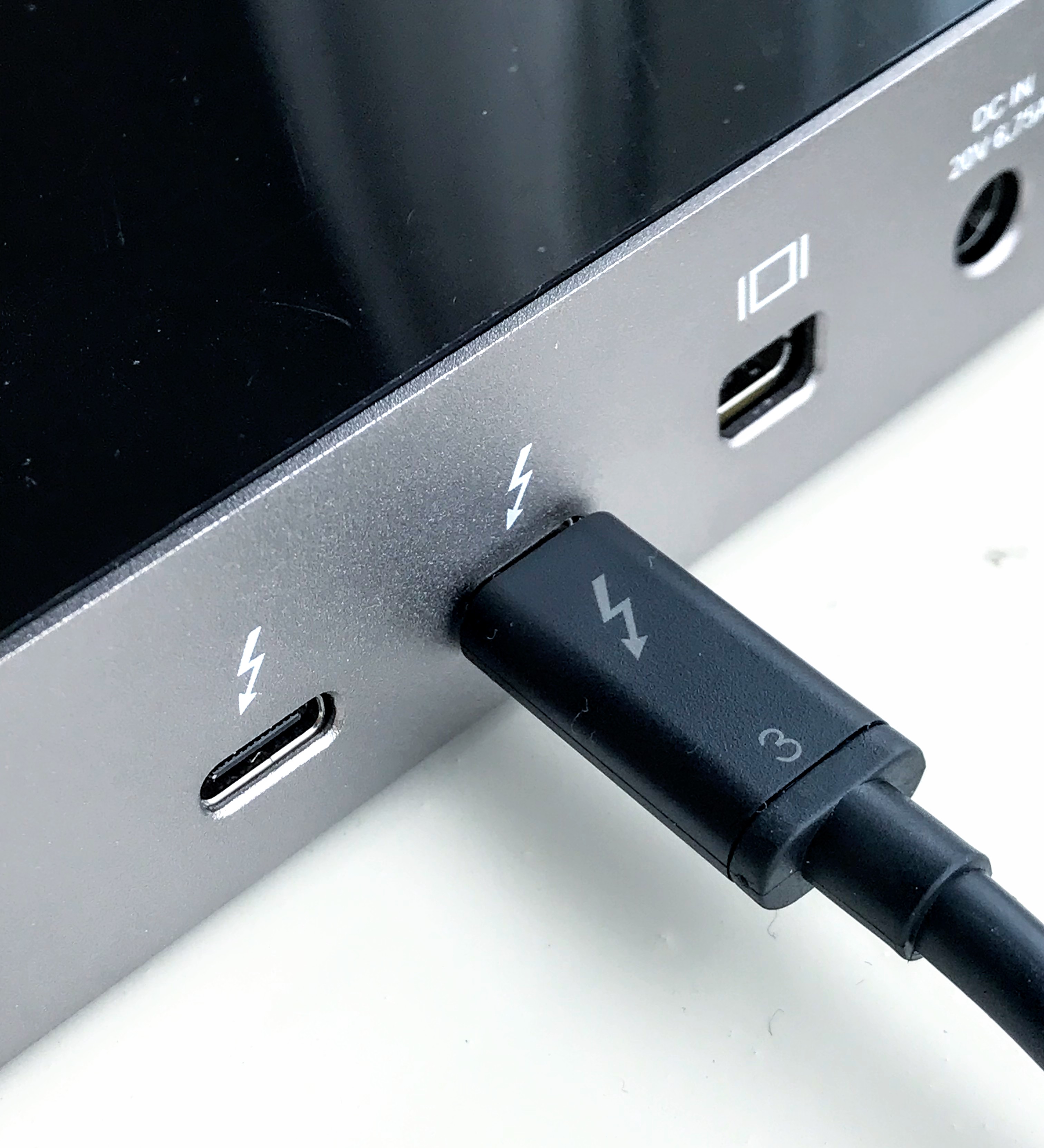 Thunderbolt 3 cable marked with a lightning symbol and 3, connected beside a matching marked USB-C-shaped dock port.